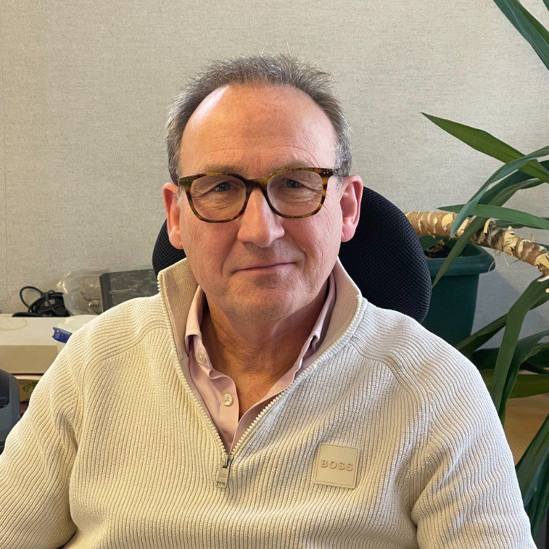 Simon Lane, Managing Director and commercial leader, smiling headshot in business casual setting.